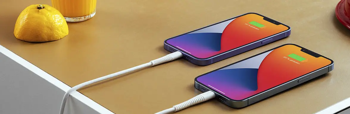 Two iPhones are lying on the table and are being charged.